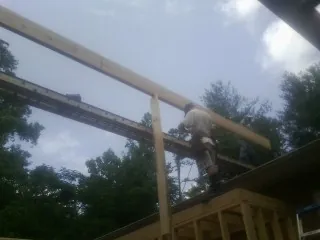 Carpenter setting a ridge beam over a new addition frame — Ice Dam Removal by Roofing Brothers in Thatcher