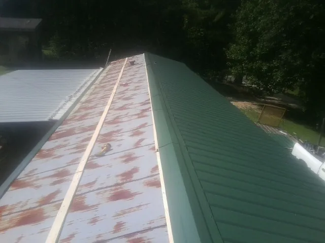 Old rusted panels beside newly installed green metal roofing — Wind Damage Roof Repair by Roofing Brothers in Thatcher