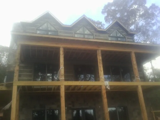 Dormers and porch framing on a large log home under construction — Roof Coating work by our crew in Thatcher