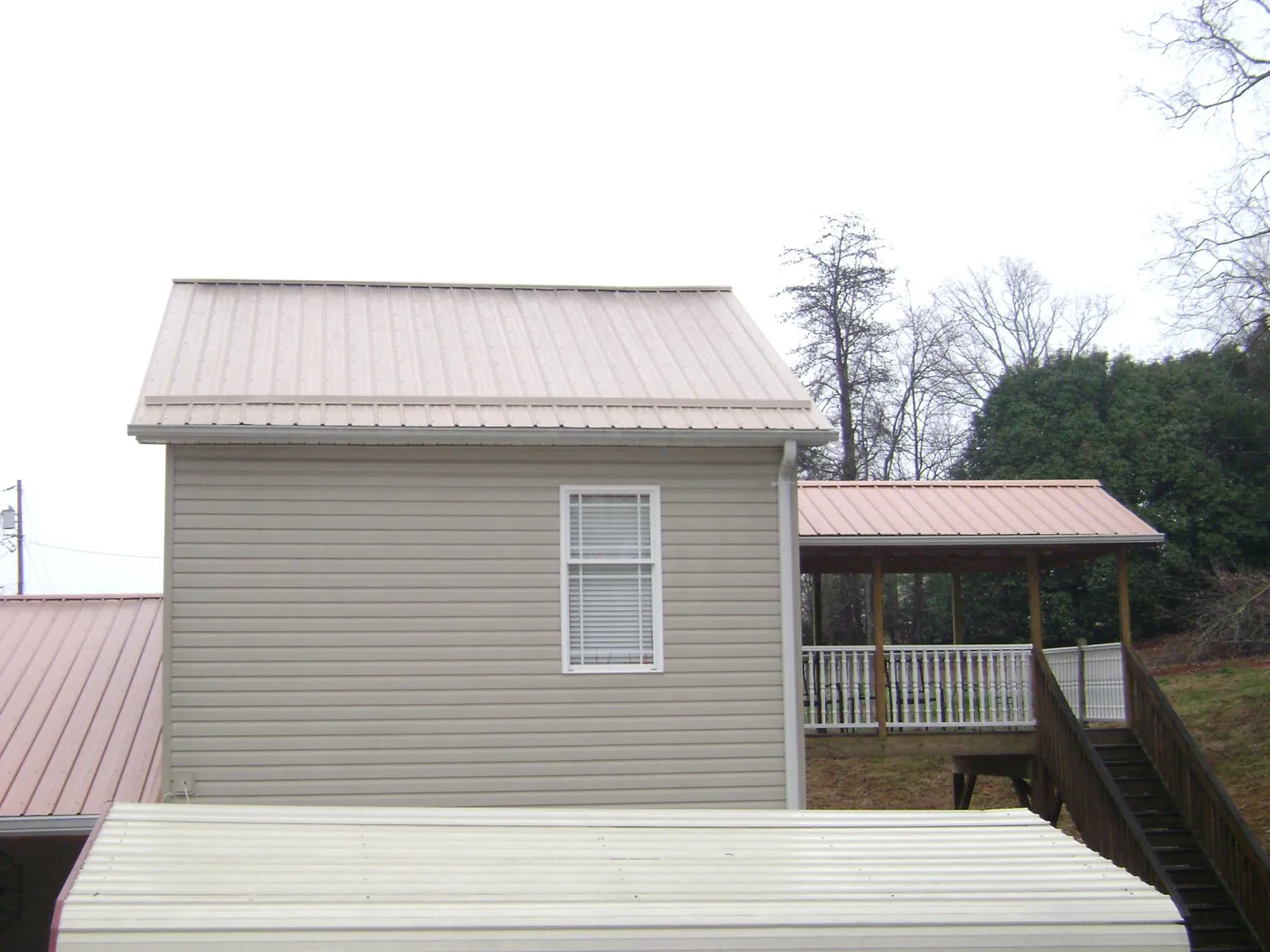 Tan metal roofs on a two story addition and attached porch, from a Roof Replacement job in Thatcher