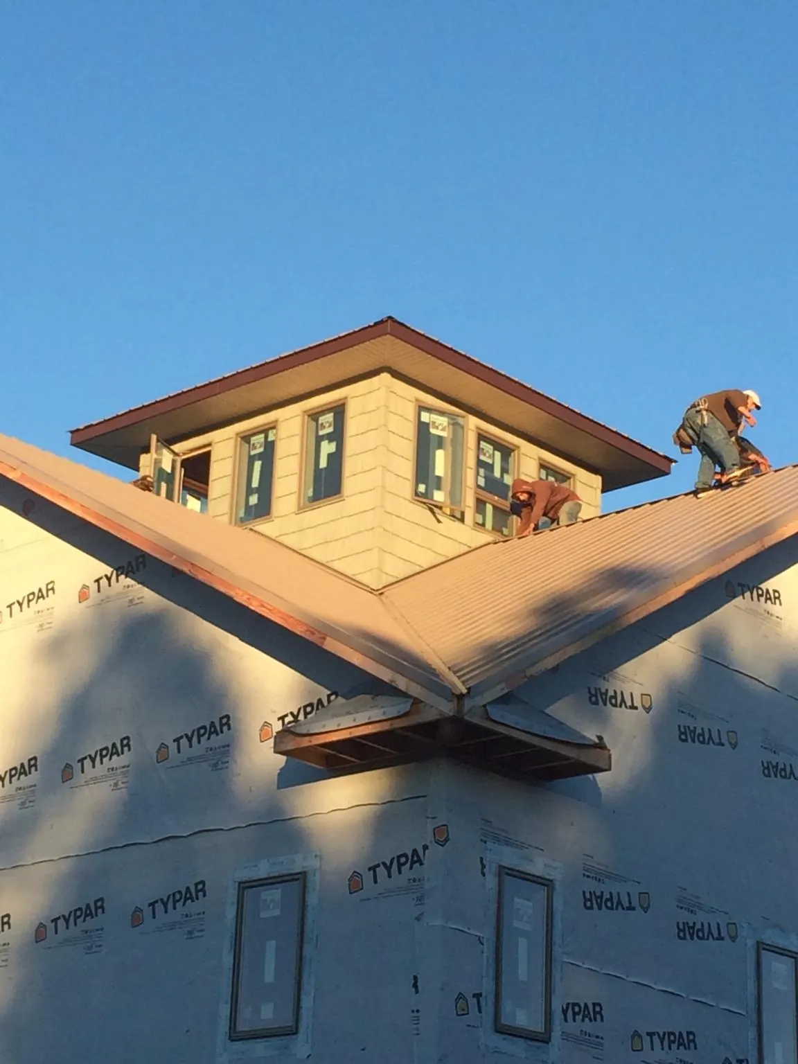 Roofers working around a rooftop cupola on a new metal roof at sunset — Roof Waterproofing in Thatcher by Roofing Brothers